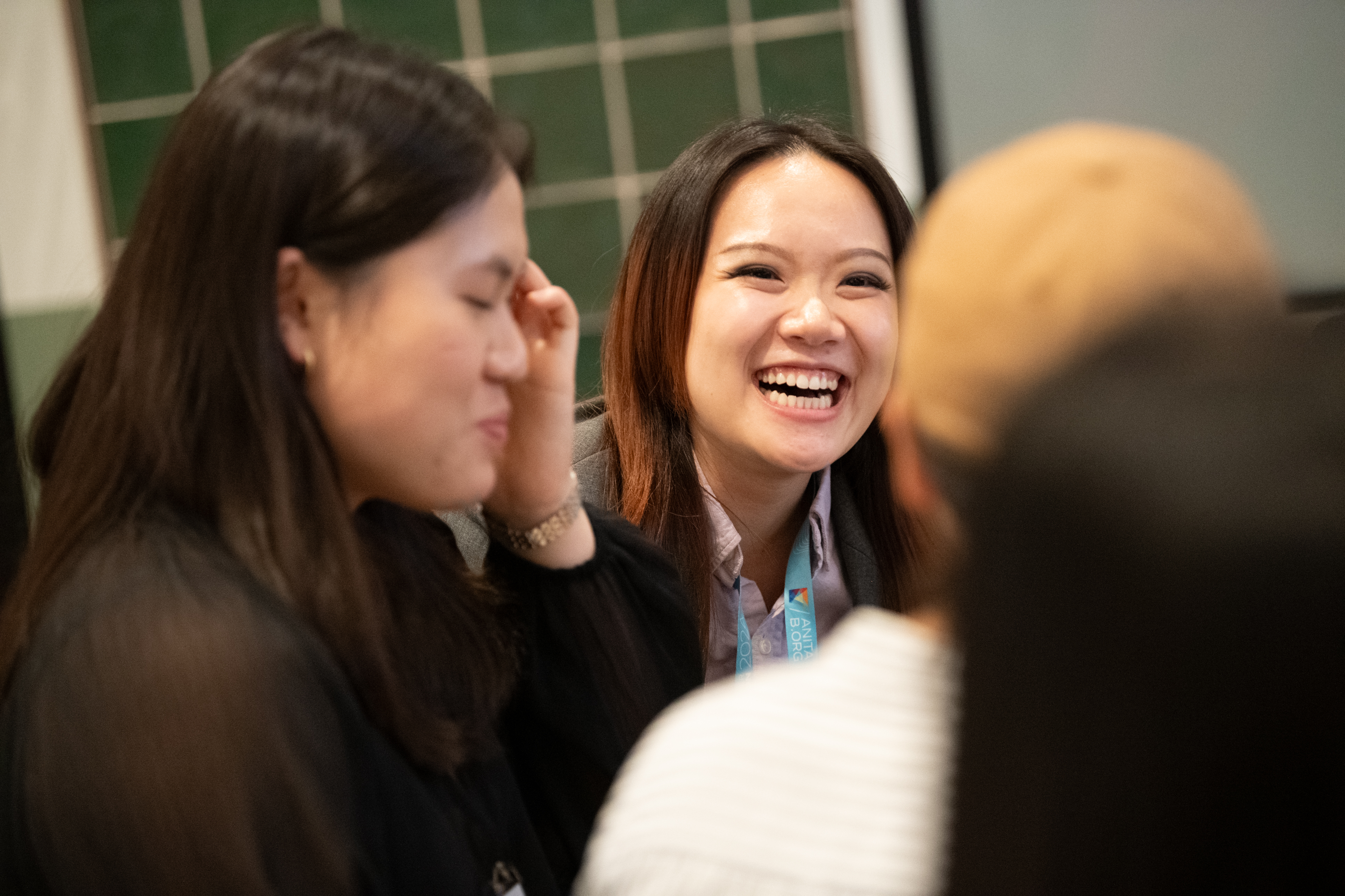 People smiling while having a conversation at the Terps in Tech alum event at the Grace Hopper Celebration